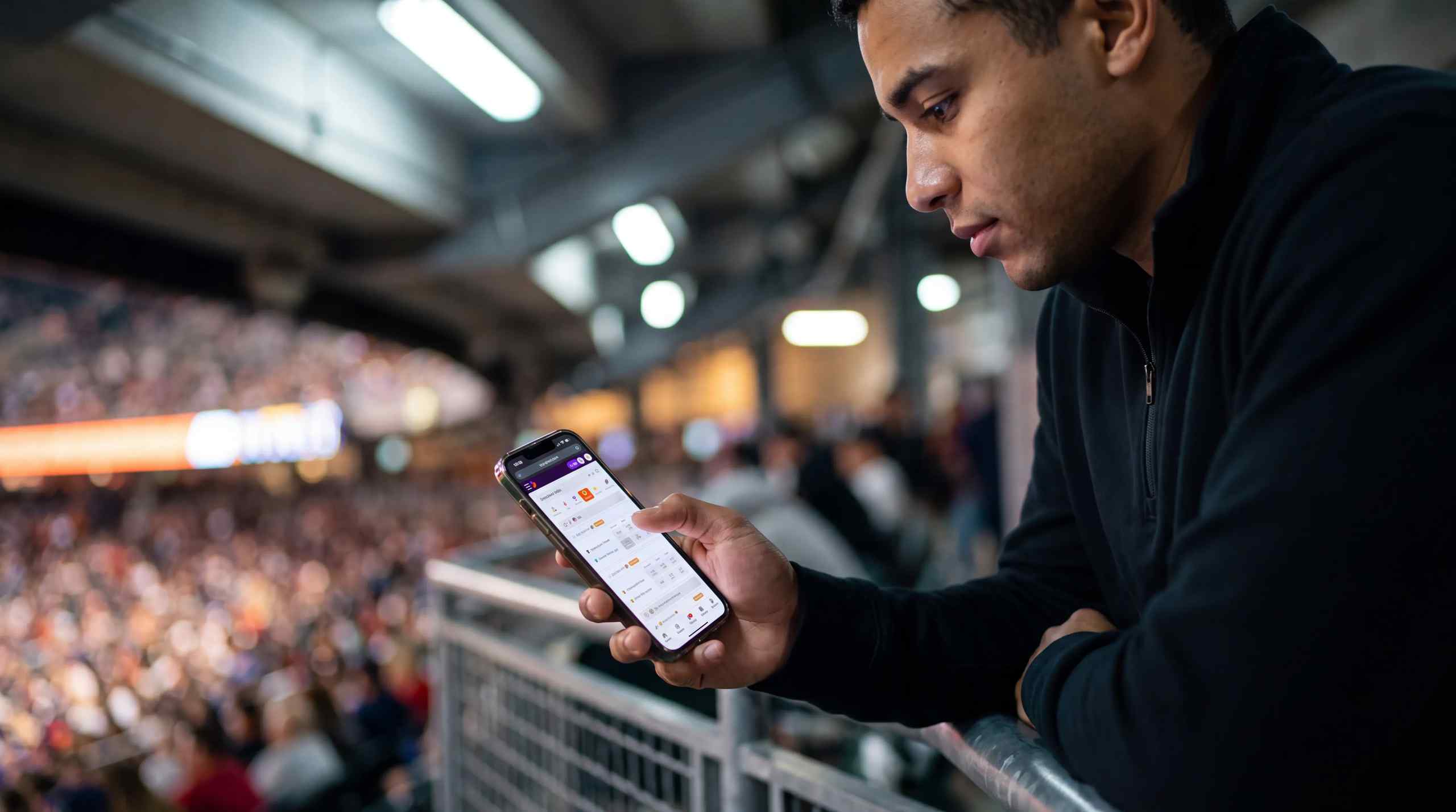 A man using a mobile casino while at a sports game.
